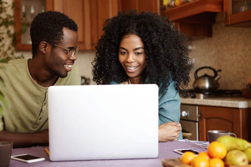 happy-young-afro-american-family-sitting-kitchen-table-surfing-internet-generic-laptop-pc-shopping-online-searching-home-appliances-people-modern-lifestyle-technology-concept