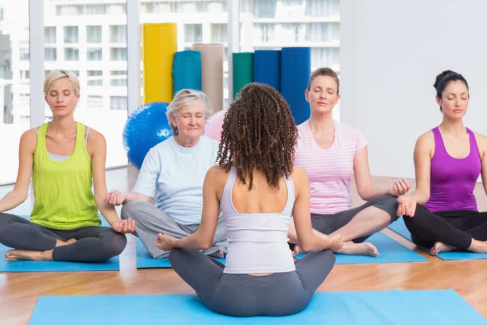 Group of people practicing lotus position in yoga class