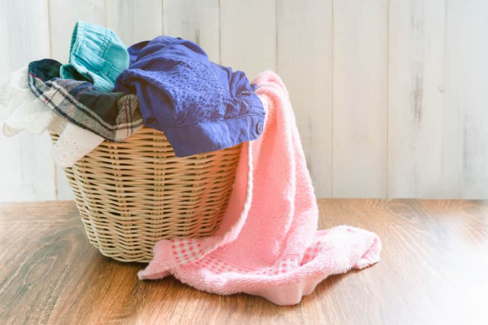 Basket with colored linen standing on the floor in the laundry room.