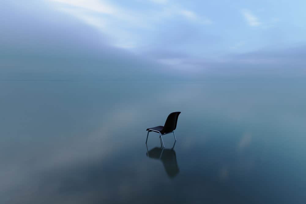 single-chair-reflecting-water-surface-stormy-day