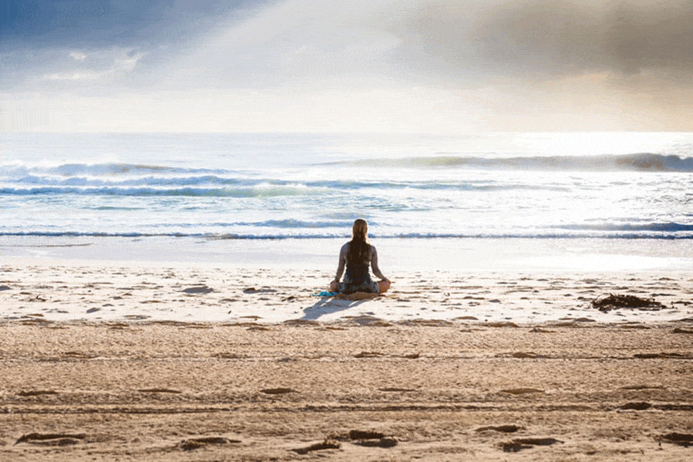 woman meditating at beach