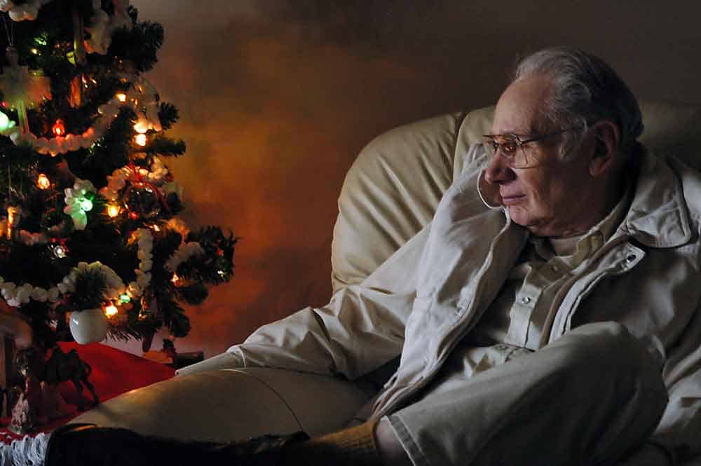 senior man looking at christmas tree