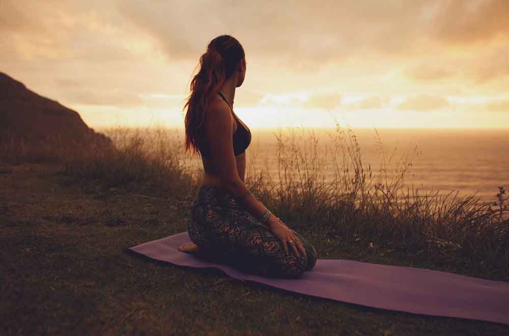 woman on yoga mat at sunse