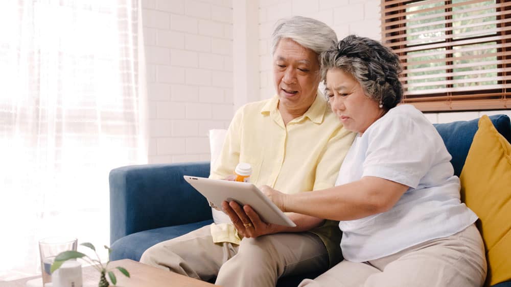 asian-elderly-couple-using-tablet-search-medicine-information-living-room-couple-using-time-together-while-lying-sofa-when-relaxed-home