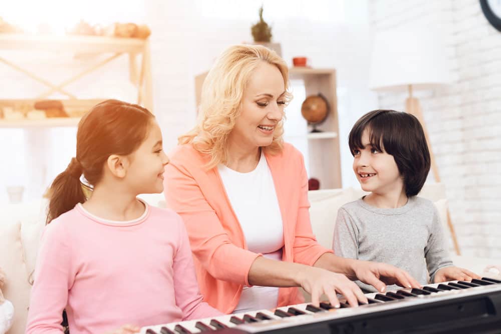 grandma-with-kids-teaching-playing-piano-home