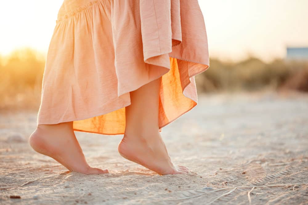 feet-woman-pink-dress-walking-sand-during-sunset