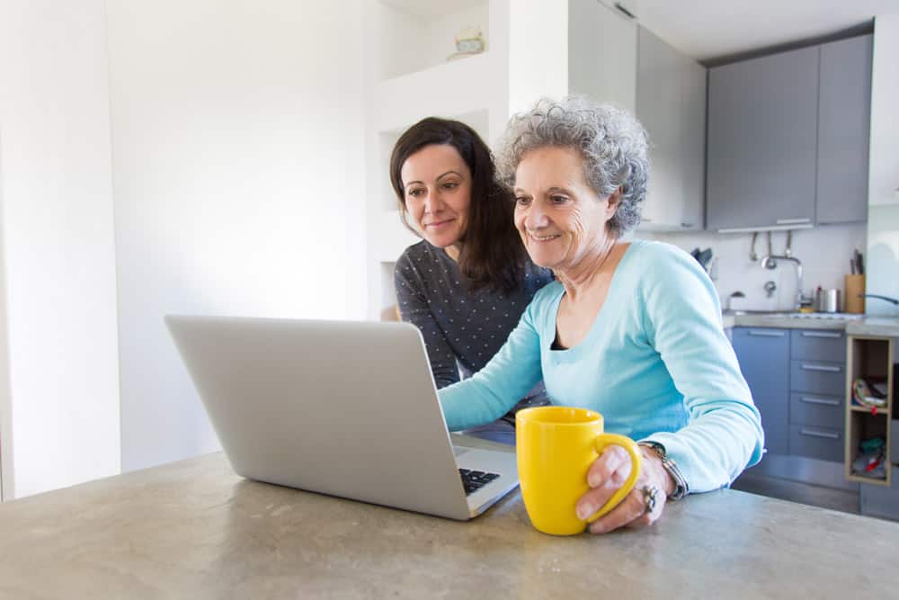 positive-senior-lady-showing-photos-daughter-laptop