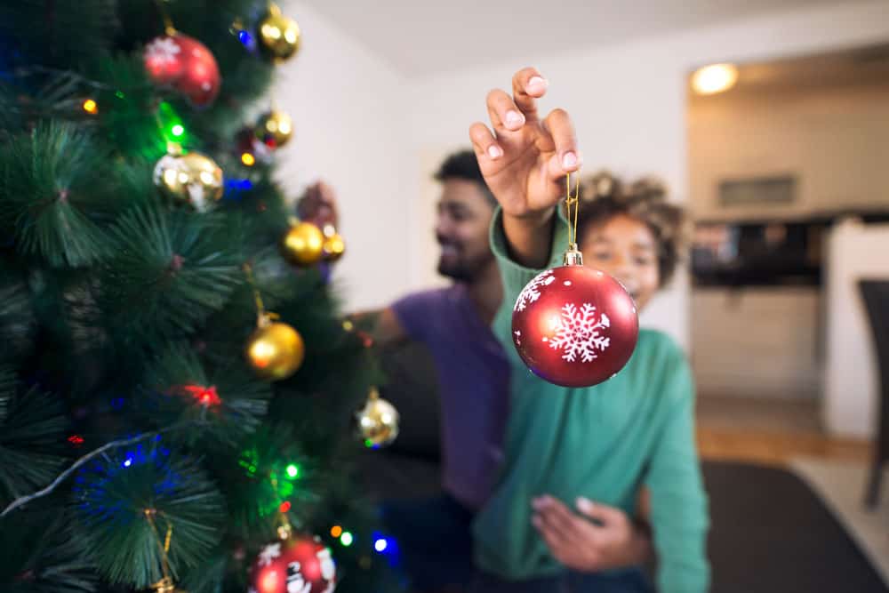 cheerful-girl-holding-christmas-decoration-enjoying-holidays