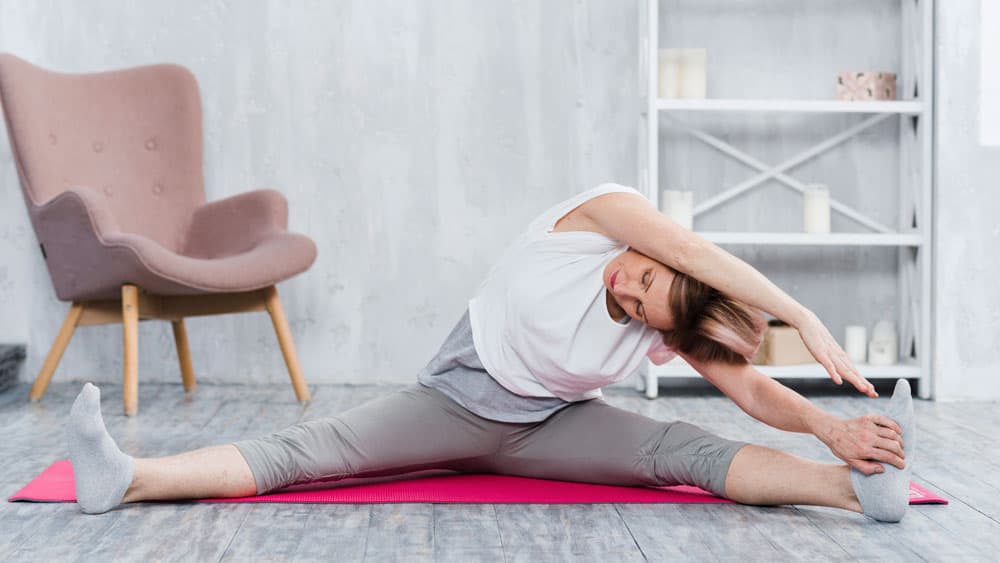 elder-woman-doing-stretching-yoga-living-room