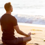 man-meditating-on-beach